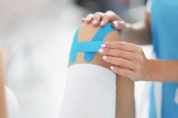 Lékař opravuje kinezio pásku na noze pacientů — Stock fotografie