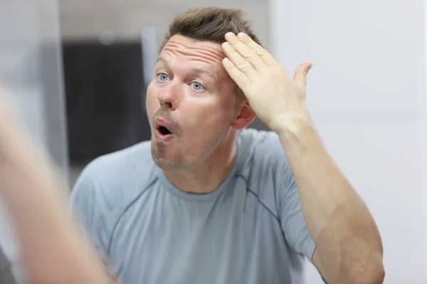 Narcistický muž před zrcadlem si dělá vlasy — Stock fotografie