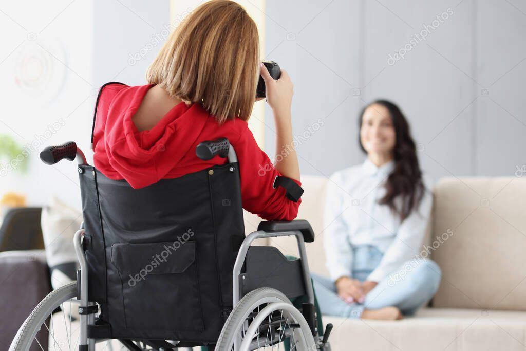 Woman in wheelchair photographs woman on couch