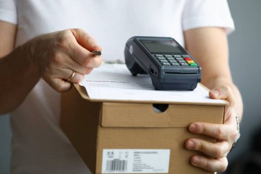 Kurye ödeme terminali ile karton kutu tutar ve kalem ile dokümanlar