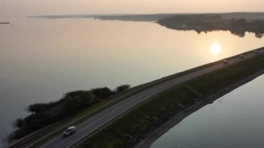 Nehrin ortasındaki köprüyle günbatımının 4K filminde çekilmiş uzun yol görüntüleri..