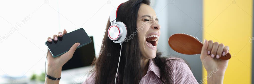 Woman with headphones and comb in her hands sings emotionally
