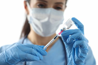 Doktor küçük şişeden şırıngaya ilaç çekiyor.