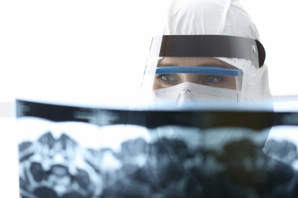 Доктор в защитном противочумном костюме смотрит на рентген