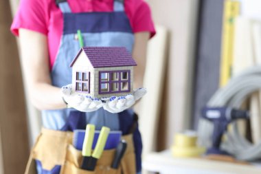 Oyuncak ahşap evi elinde tutan kadın inşaatçı.