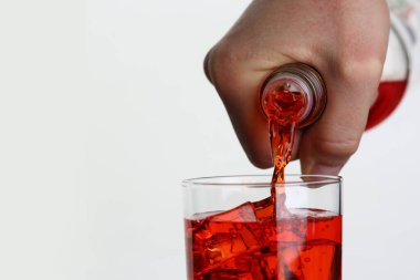 Portakal suyu bardağa dolduran bir adam.