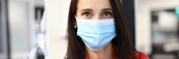 Woman hairdresser in medical mask holds scissors in hand