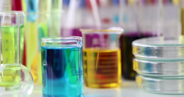 Химическое стекло с разноцветной жидкостью, стоящей на столе в лаборатории 4k фильма — стоковое видео