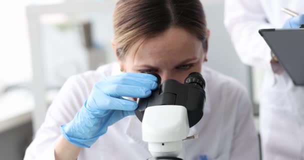 Donne biologi guardando attraverso il microscopio in laboratorio 4k film — Video Stock