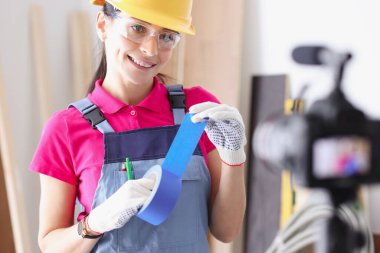 İnşaatçı blogcu kamerada onarımlar için mavi koli bandı gösteriyor