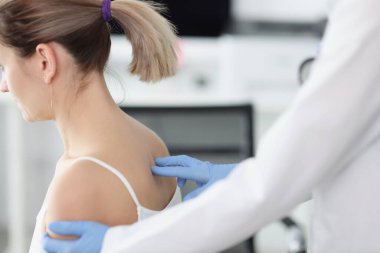 Doktor muayenehanedeki hastanın omurgasını muayene ediyor.