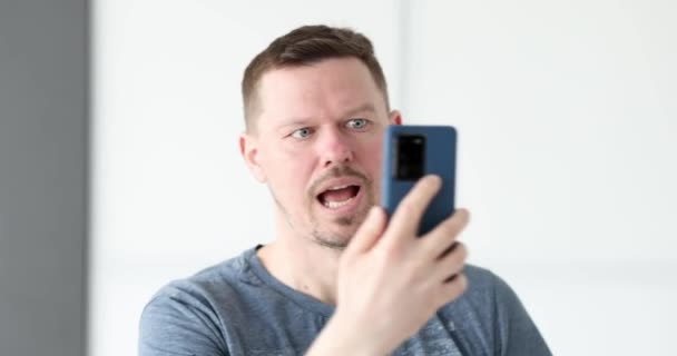 Junger Mann mit Handy in der Hand schreit und hält seinen Kopf 4k Film — Stockvideo