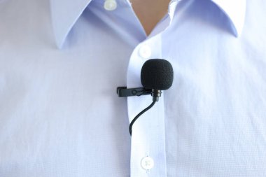 Erkek gömleğine takılan siyah küçük mikrofon.