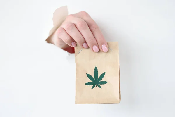 Рука вытаскивает бумажный пакет марихуаны из рваной бумаги — стоковое фото