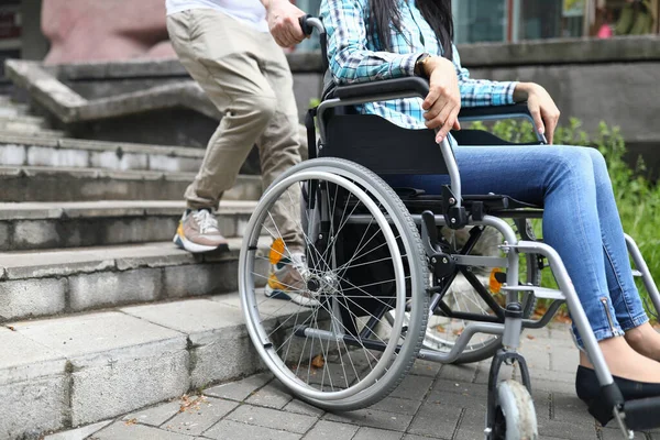 Man tries to drag wheelchair with woman onto stairs — Stock Photo, Image