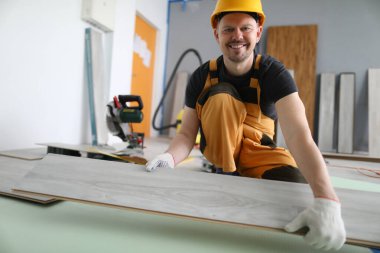 Sert şapkalı gülümseyen usta lamine tahtayı tutuyor.