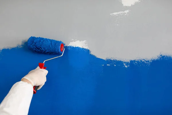 Master painter paints wall bright blue closeup