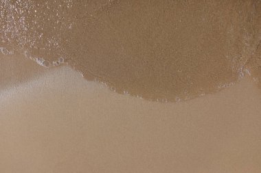 Islak kum ve suyla kaplanmış kumsal.