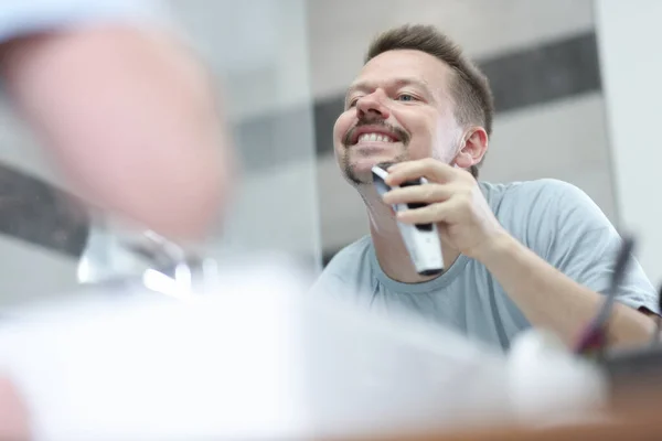 Człowiek goli swój zarost maszyną przed lustrem — Zdjęcie stockowe