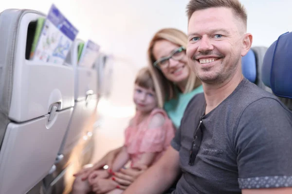 Sonrientes padres con niño están sentados en cabina de avión — Foto de Stock