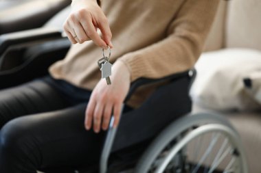 Woman in wheelchair holds keys to apartment clipart