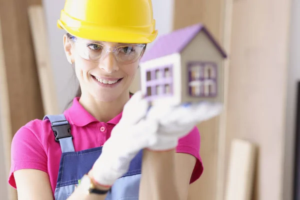 Leende kvinna byggmästare hålla hus i hennes händer — Stockfoto