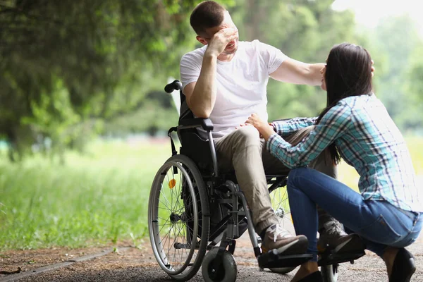 Niepełnosprawny mężczyzna na wózku inwalidzkim komunikuje się z kobietą w parku — Zdjęcie stockowe