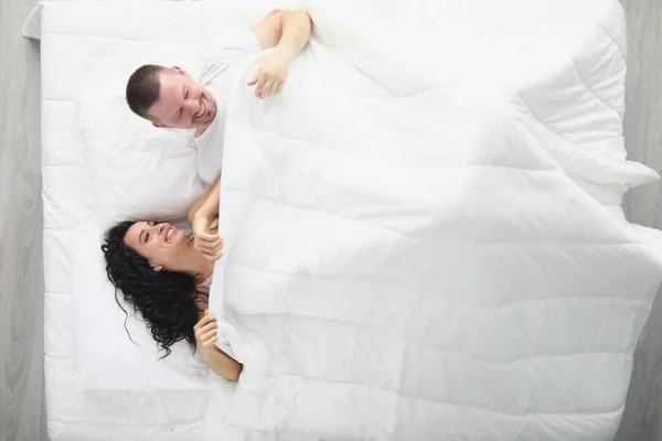 Riendo hombre y mujer en cama blanca grande — Foto de Stock