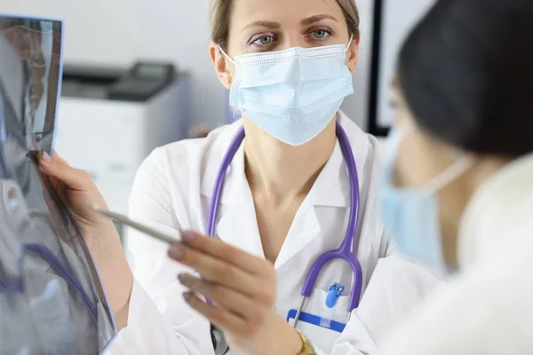 Un médecin portant un masque médical de protection montre une radiographie du patient — Photo