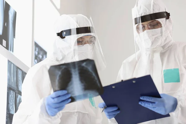 Two doctors in protective suits and masks examine X-rays — Stock Photo, Image