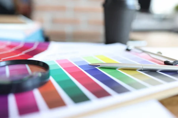 Color palette with pen and magnifying glass is on table — Stock Photo, Image