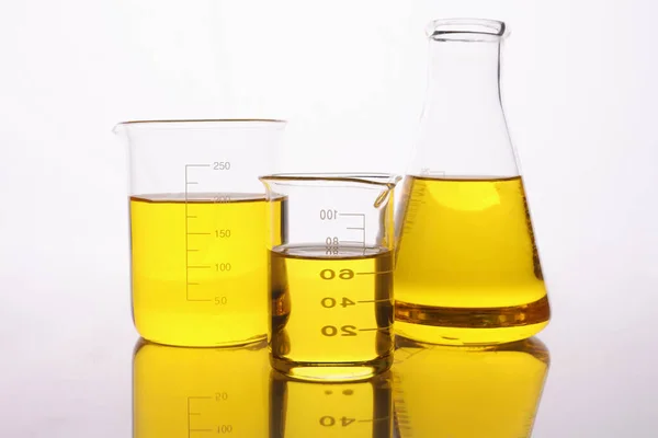 Chemical test tubes and flasks with yellow oil — Stock Photo, Image