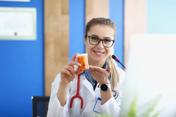 Mujer doctora sosteniendo frasco de cápsulas en su clínica de manos —  Fotos de Stock