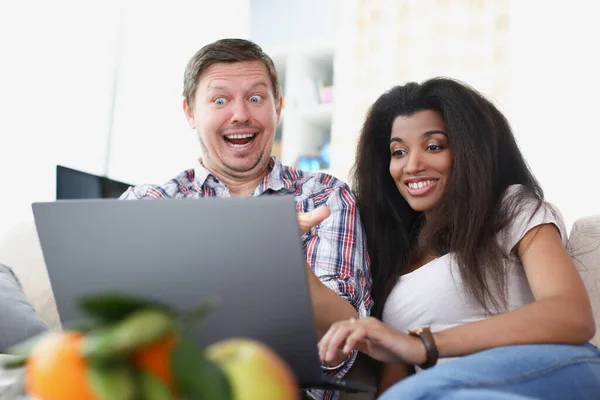 Ung man och kvinna sitter framför laptop skärmen och ler — Stockfoto