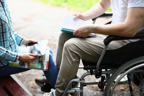 Man i rullstol och kvinna håller digital tablett och läroböcker närbild — Stockfoto