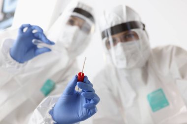 Beyaz takım elbiseli doktorlar hastaların yakın çekimlerinden örnek alıyorlar.