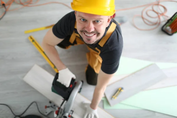 Carpinteiro em chapéu duro de corte laminado com serra elétrica vista superior — Fotografia de Stock