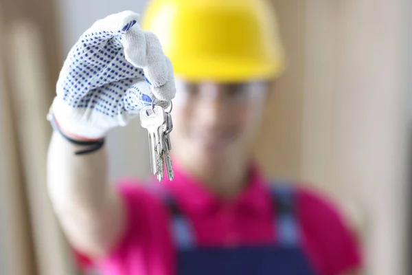 Woman builder in protective helmet holding keys in hands closeup