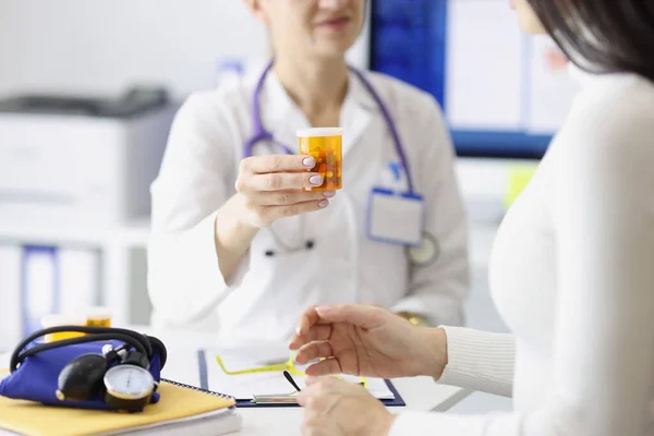 Médico dando frasco de medicamentos a la mujer joven en primer plano clínica — Foto de Stock