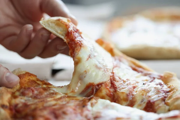 Man tearing off piece of delicious pizza with his hand closeup — Stock Photo, Image