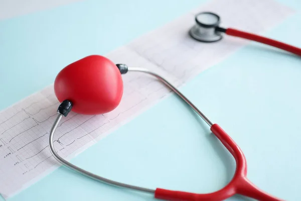 Червоне іграшкове серце і стетоскоп, що лежить на кардіограмі крупним планом — стокове фото