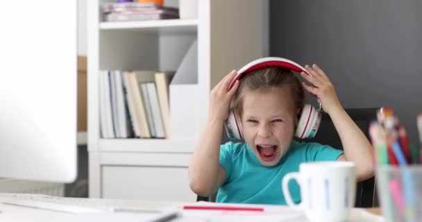 Liten flicka med hörlurar lyssnar på musik och sjunger på dator 4k film — Stockvideo