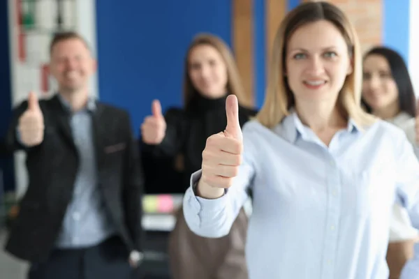 Mujer mostrando pulgar hacia arriba contra el fondo del equipo de colegas primer plano —  Fotos de Stock