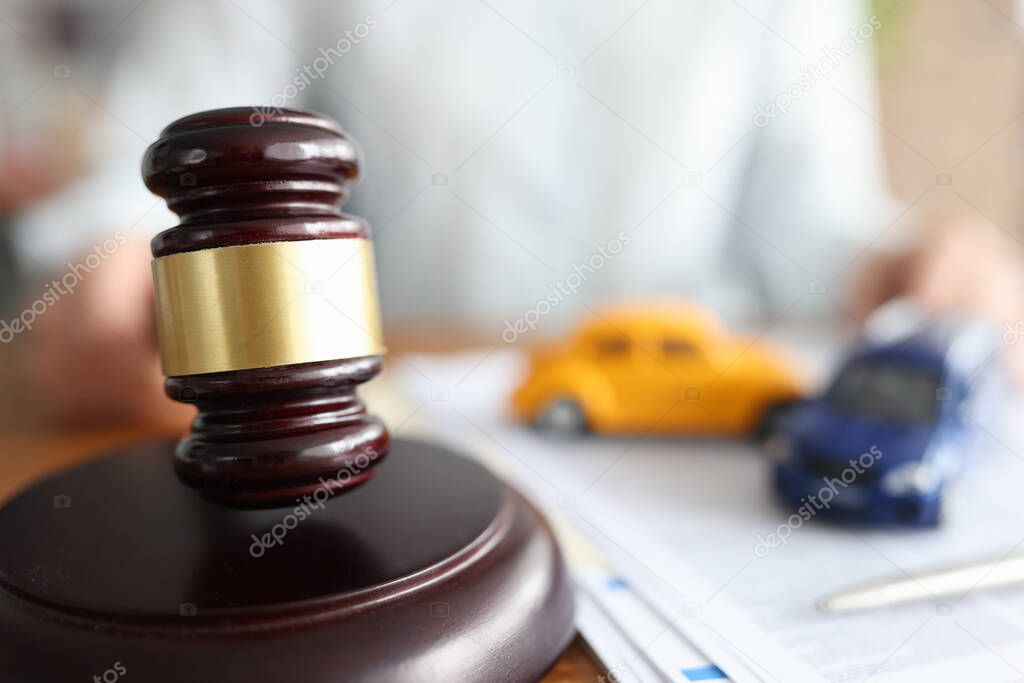 Judge holding hammer near toy cars closeup
