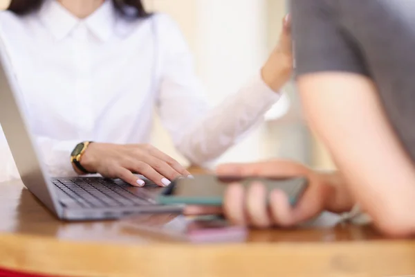 Man and woman communicating at table with laptop closeup