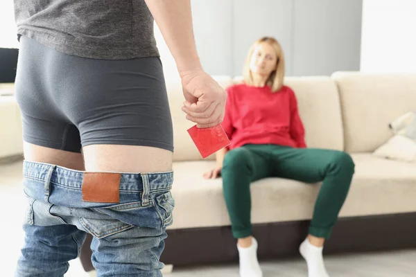 Man staan voor vrouw zonder broek en het houden van condoom in handen closeup — Stockfoto