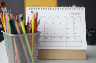 Calendar for May with colored pencils is on table