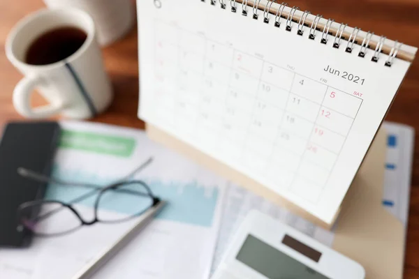 Calendar for June calculator and cup of tea is on table — Photo