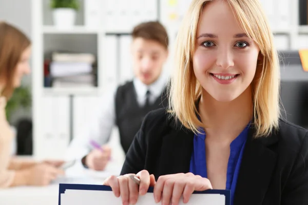 Portrait of young businesswoman in office against background of colleagues — Stock Photo, Image