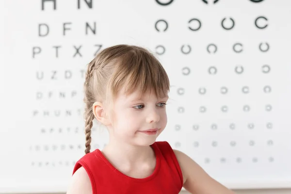 눈 검사를 받기 위해 탁자 가까이 앉아 있는 어린 소녀 — 스톡 사진